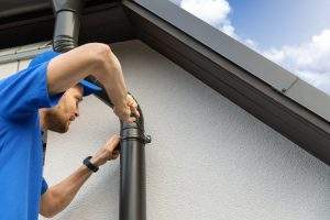 worker installing house roof gutter